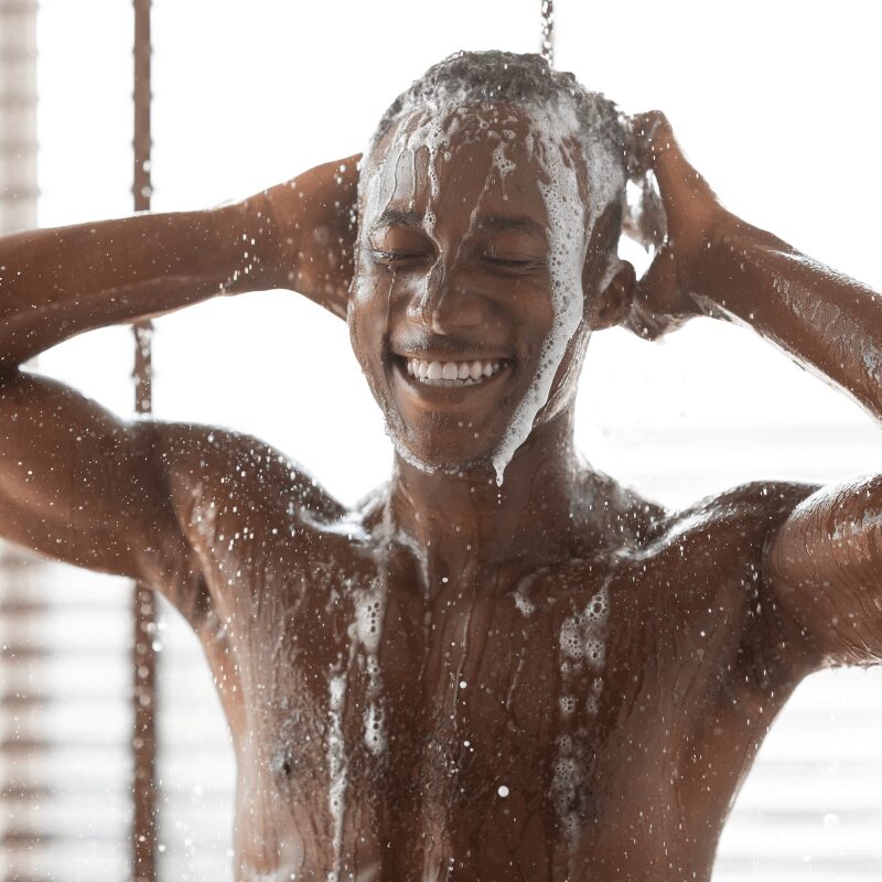 black man washing head in shower